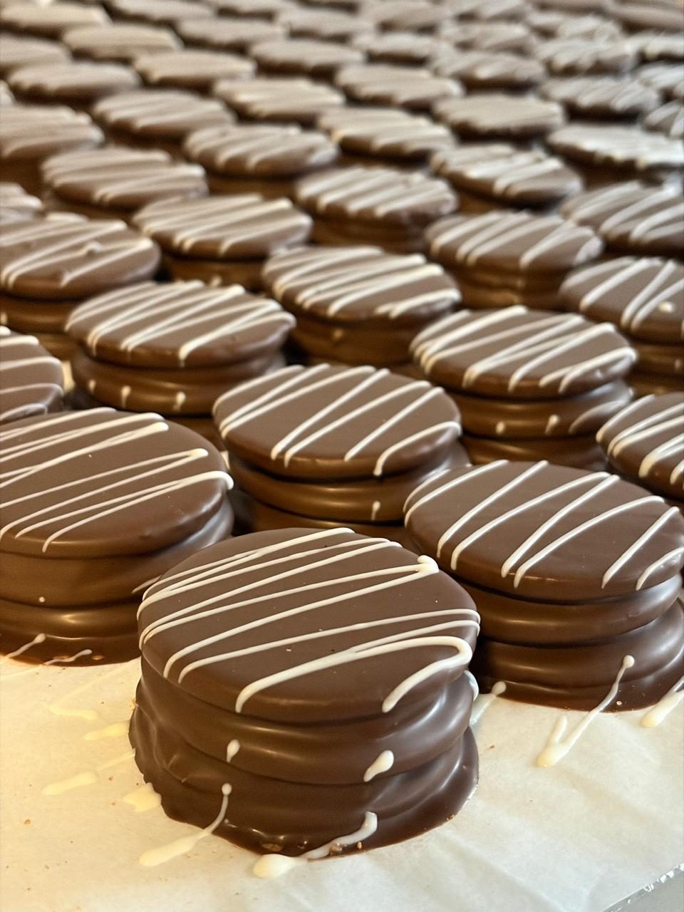 Alfajores bañados en chocolate con hilo de chocolate blanco