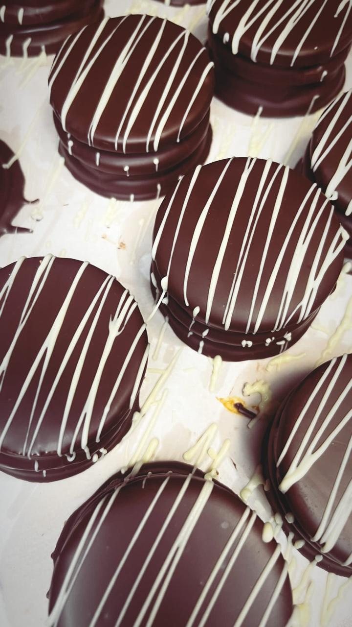 Alfajores bañados en chocolate con hilo de chocolate blanco
